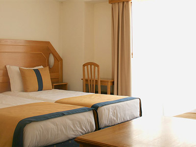 Two single beds in a room with wooden furniture at Hotel do Chile