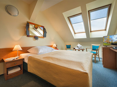 A single bed in a room with bedside tables, places to sit and watch TV at at EA Tosca Hotel