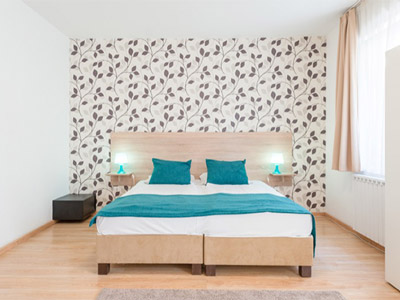 A double bed with blue sheets and a patterned wall behind it at Prince Apartments - Rank #8