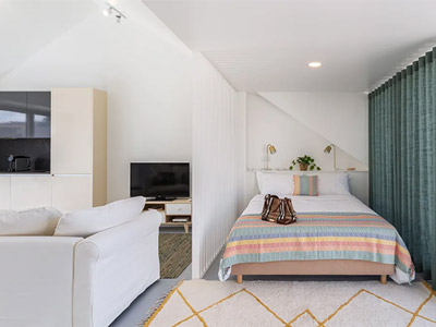 A double bed in a room with a lounge area beside it at Suceed Campo Pequeno Apartments