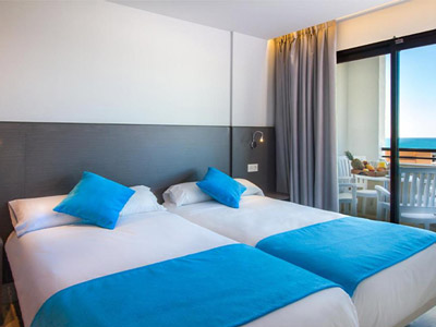 Two single beds beside a large window that opens onto a balcony at La Era Park Apartments