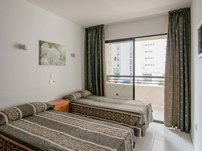 A twin room with brown and beige interior at Luxmar Apartments in Benidorm
