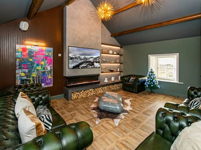 A lounge area with a tv, multiple green leather sofas and warm decor at Natterjack Manor House
