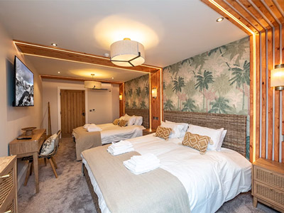 Two double beds in a room with a TV and warm LED lighting, with palm tree wallpaper behind it at Middleton Manor