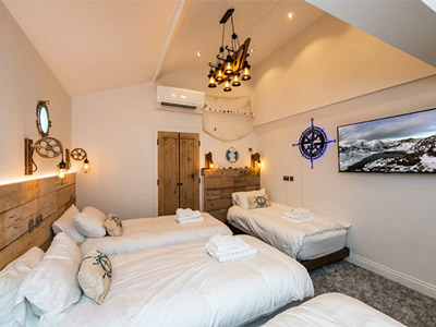A room with multiple beds, a large TV and warm lighting at Middleton Towers