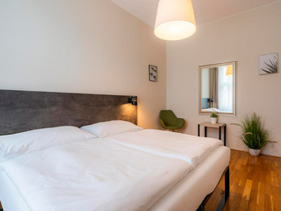 A double bed in a room with a mirror and green plants at Melantrich Apartments