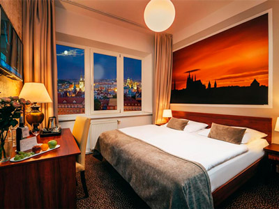A large bed in a room with a TV and a view of the city from the windows at Metropolitan Old Town Hotel