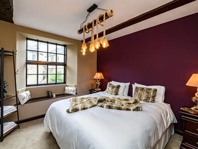 A double bed in a room with large windows and warm lighting at Black Swan Manor
