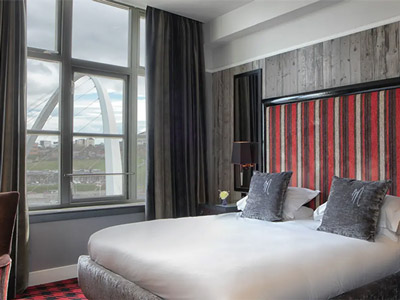 A double bed in a room with a window that overlooks the millennium bridge at Malmaison in Newcastle