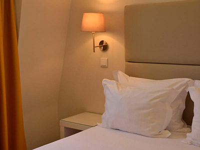 A close up of a bed surrounded by warm lighting at Porto Domus Hotel