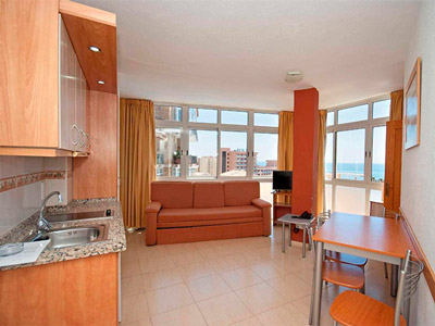 An open plan kitchen and lounge area with large bay windows at Doramar Apartments