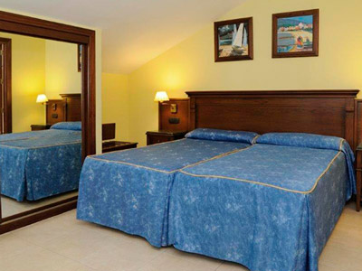 A blue bed in a yellow room with a large mirror beside it at Hotel Vivema