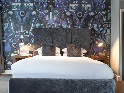 A king bed in a room with patterned wallpaper behind it at Malmaison in Leeds