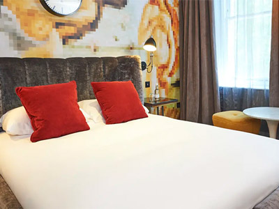 A bed with red cushions and a patterned wall behind it at Malmaison in London 