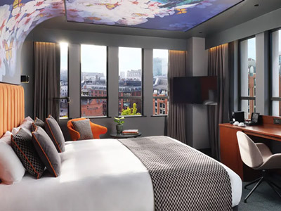 A king bed in a room with large windows that overlook the city at Malmaison Manchester Deansgate