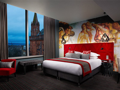 A spacious double bedroom at Malmaison with a large double bed, city views and a striking art mural behind the bed 