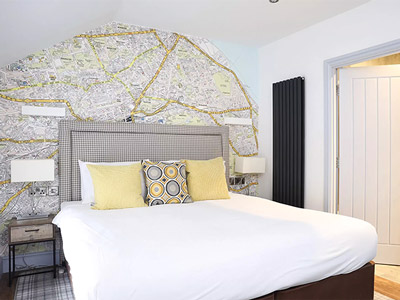 A bedroom with a double bed and map themed decor 
