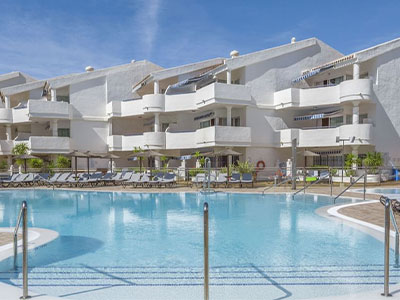 The Sahara Sunset hotel with a large outdoor swimming pool that has sun loungers around it 