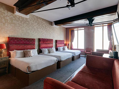 A room in Boutique 56 with three beds and a large sofa 