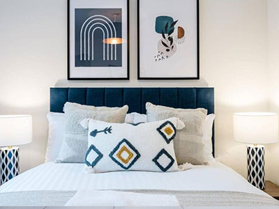 A bedroom at The Coach House that has a double bed with stylish patterned cushions and wall art above the bed 