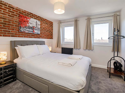 A bedroom at Walpole House which has a double bed and a wall with exposed brickwork 