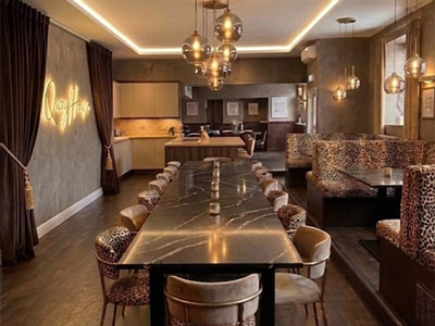 A dining room at Quay House with a long dining table and booth seating that has a leopard skin print 