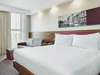 A room at Hampton by Hilton Bristol which has a double bed, a sofa bed and bristol themed wall art 