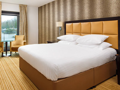 A king bed in a room with a table and set of chairs and a large window at Delta by Marriott in Nottingham