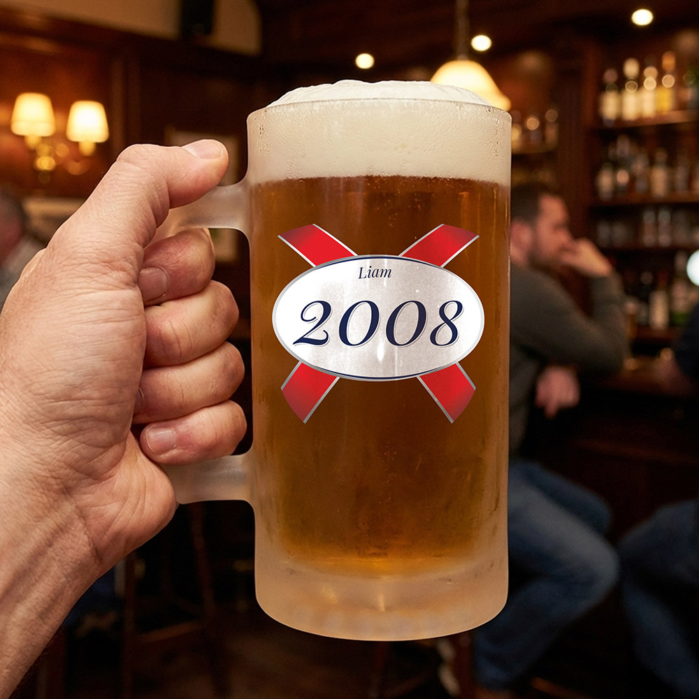 A custom birthday stein with clear glass and a Kronebourg 1664 design where the 1664 has been swapped for 2008 and has the custom text Liam on it 