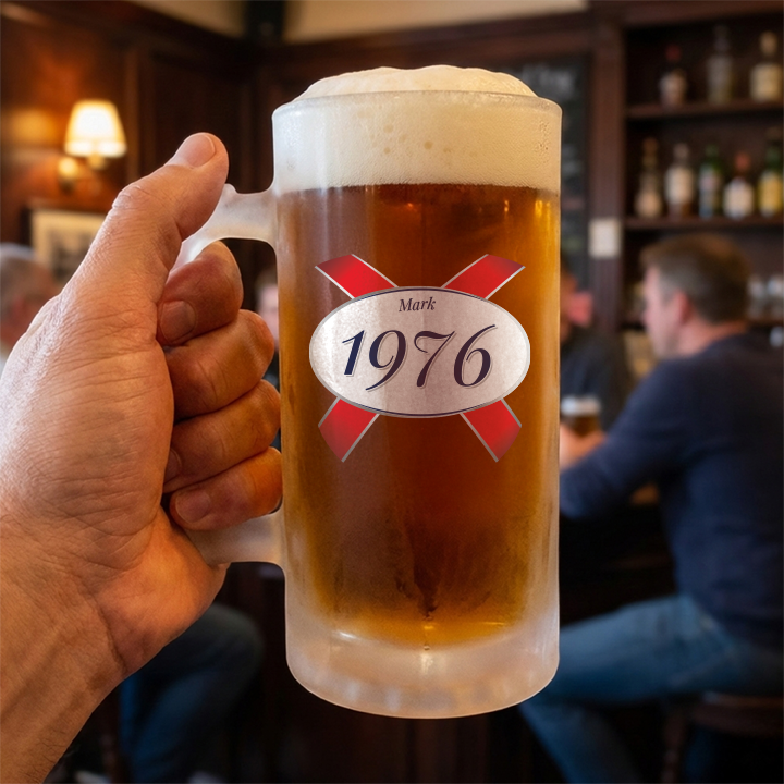A custom 50th birthday stein with frosted glass and a Kronebourg 1664 design where the 1664 has been swapped for 1976 and has the custom text Mark on it 