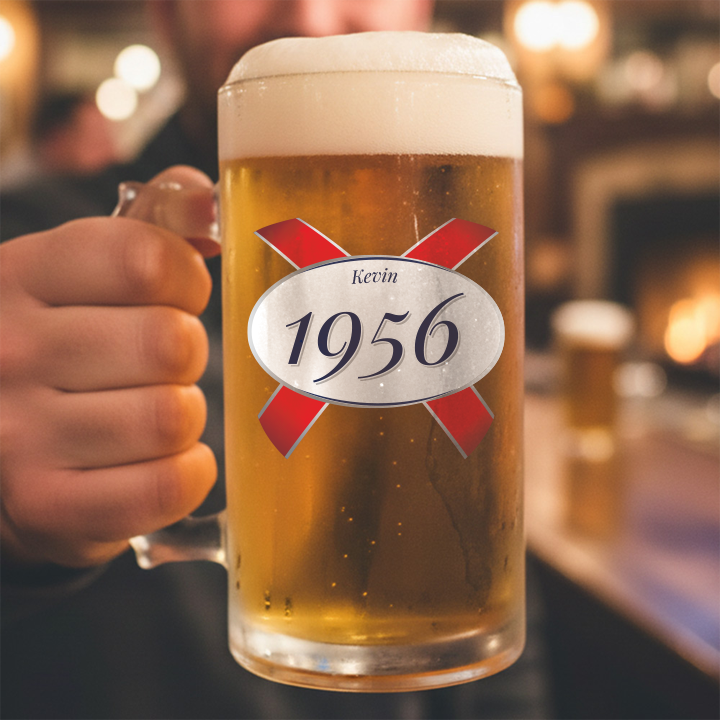 A custom 70th birthday stein with clear glass and a Kronebourg 1664 design where the 1664 has been swapped for 1956 and has the custom text Kevin on it