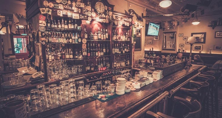 Image of a bar with shelves of alcohol and glasses stacked up