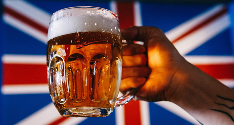 A hand holding a big jug of beer in front of a union jack