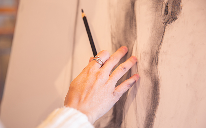 Someone holding a pencil and touching a drawing they have done 