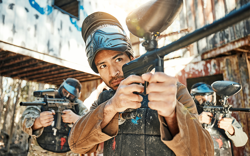 Three men holding paintball guns and aiming them 