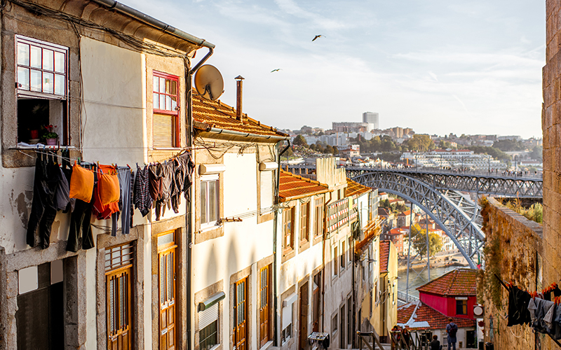A quaint looking Porto street with the The Dom Luís I Bridge in the background 