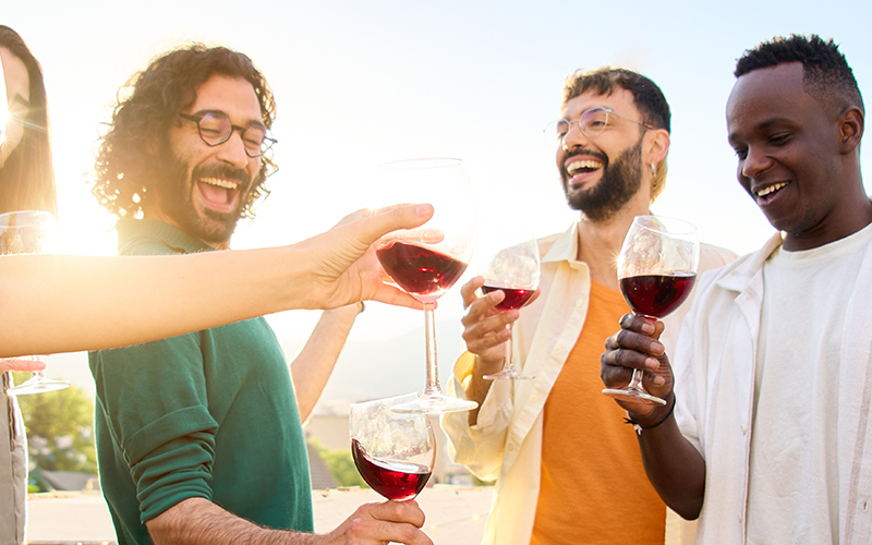 A group of men laughing and clinking wine glasses 