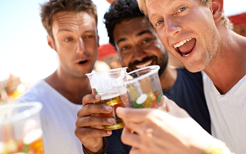 Three men making a toast with plastic cups full of beer. 