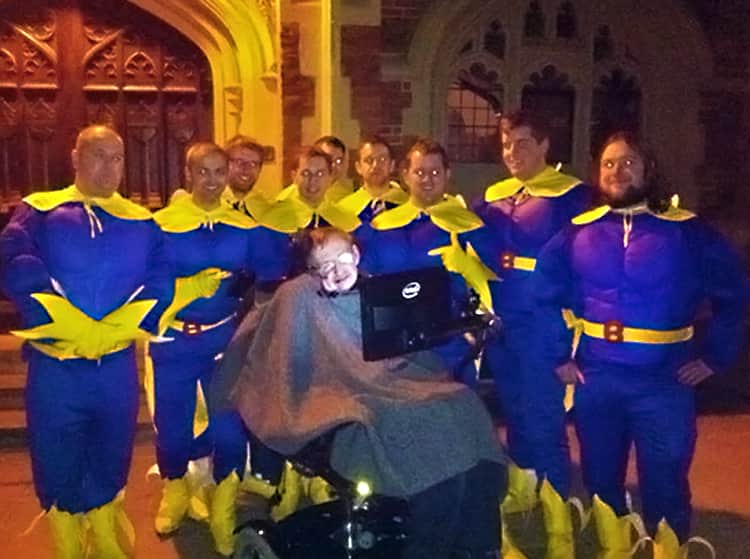 Stephen Hawking posing for a picture with a group of men dressed as Bananaman