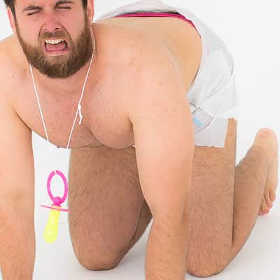 A man on all fours in a baby outfit