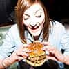 A woman working for LNOF attempting tucking into the dAt Burger at dAt bAr, Newcastle Upon Tyne