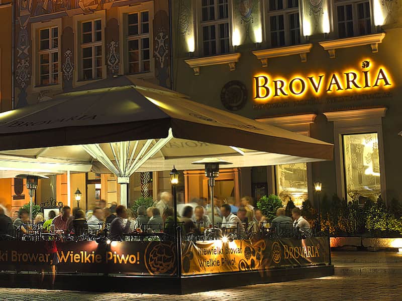 A close up of the Brovaria Hotel with people sitting outside in the restaurant