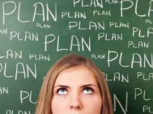 A woman looking up to the backdrop of a board with 'plan' written on several times