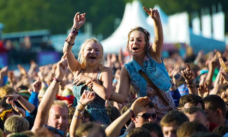 Girls at a festival with their hands in the air
