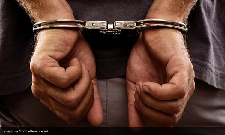 Close up image of a man's hand handcuffed behind his back