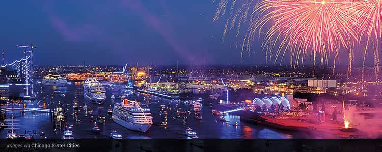 The marina of Hamburg at night, filled with boats and with pink fireworks exploding in the sky