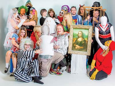 An image of people in Halloween costumes posing in a white studio 