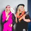 Two women posing in a photobooth with props