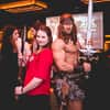 A man dressed as Conan the Barbarian, posing with a woman in a red top