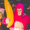 A man dressed as a pink gorilla and holding an inflatable yellow banana, with others around him